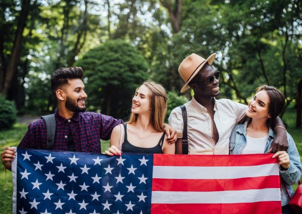 happy-four-students-relaxing-nature-with-american-flag-celebrating-4th-july